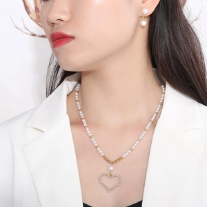 Gros plan d'un mannequin portant un collier de perles, pendentif cœur doré et boucles