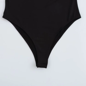 Detail shot of the high-cut leg opening on a black long sleeve bodysuit made of elastic fabric