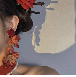 Detail showing red 3D floral earrings and matching hair stick with pearl accents