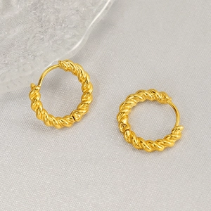 Elegant gold twisted hoop earrings with a textured rope design on a soft fabric background