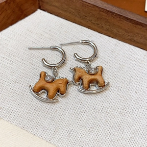 Détail de boucles d'oreilles cheval à bascule argent avec cristaux et perle sur bois