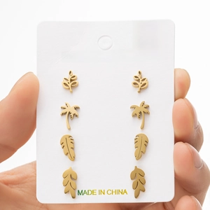 Detail of four pairs of gold stainless steel leaf and palm tree stud earrings on card