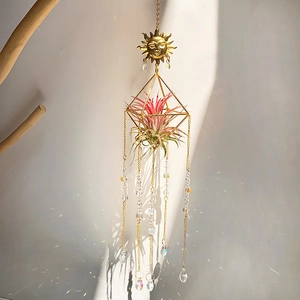 Golden sun face metal suncatcher with crystal prisms creating rainbow light spots on wall