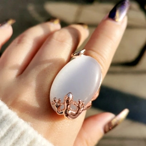 Macro shot of rose gold lizard ring with large oval white opal on model finger
