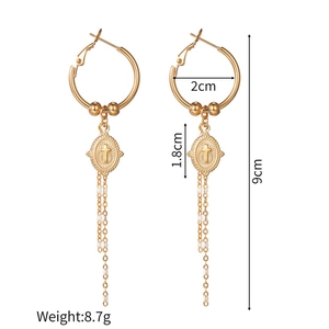 Detail view of gold cross oval earrings with white beads and measurements for length and weight