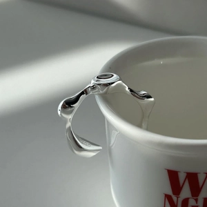 Minimalist S925 sterling silver irregular molten ring hanging on a white ceramic cup