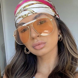 Stylish large metal frame aviator sunglasses with orange tinted lenses on female model