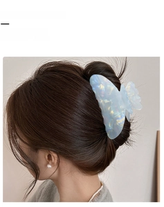 Détail d'une grande pince à cheveux papillon bleu clair avec texture marbrée sur cheveux