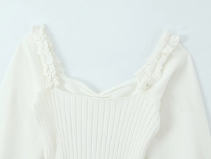 Macro shot of white ribbed knit top showing ruffle strap and elegant neckline details