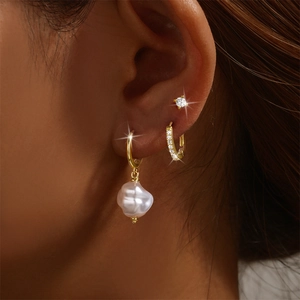 Detail of 925 silver gold-plated earrings set with baroque pearls and zircon on model