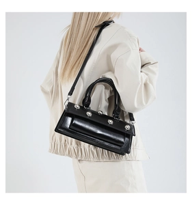 Detail of glossy black baguette bag with five silver spherical studs and dual handles