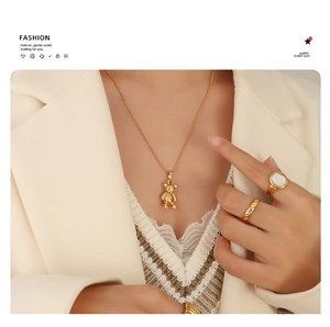 Detail of 18K gold plated bear necklace and ring set worn with a white blazer