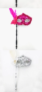 Detail of handheld Venetian sequin masks with elegant feathers in magenta and silver