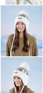 Detail of winter trapper hat featuring faux fur pom-pom, ear flaps and leather brand label