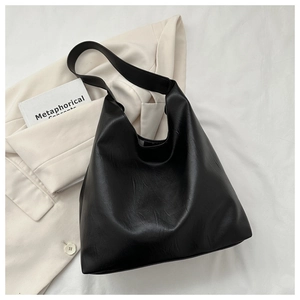 Close-up of black PU leather hobo bag with natural textures on a white blazer background