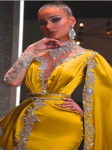 Detail van gele satijnen jurk met zilveren strass-steentjes en borduursels op de halslijn