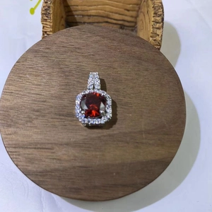 Macro shot of square red gemstone pendant with zircon halo on a wooden display stand