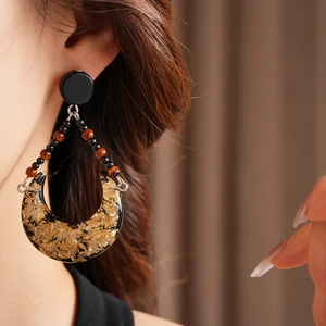 Detail of vintage moon crescent earrings with gold foil in resin on model's ear