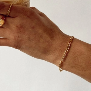 Close-up of golden Figaro chain bracelet on wrist showing flat link design details