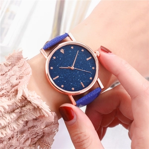 Macro di orologio cielo stellato oro rosa con cinturino in pelle blu sul polso