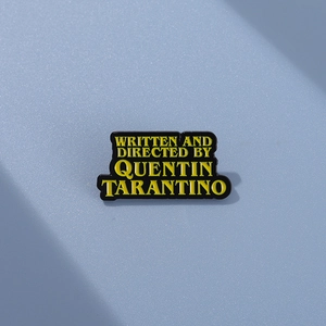 Detail of Quentin Tarantino enamel badge with yellow text on a blue matte background