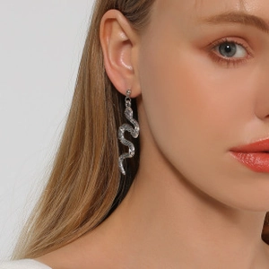 Detail of silver snake-shaped drop earrings with textured scales on earlobe