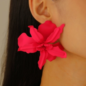 Close-up of oversized magenta 3D flower earrings with a smooth matte lacquer finish