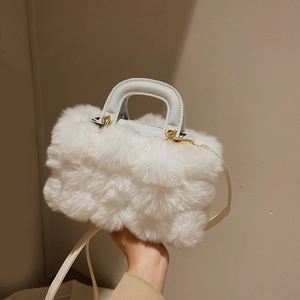 White faux fur handbag with leather handles and crossbody strap on beige background