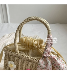 Detail of straw woven bag with floral scarf handle and drawstring cotton lining