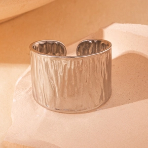 Macro shot of wide silver titanium steel cuff with unique hammered bark texture on stone