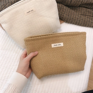 Detail of woven lattice texture cosmetic bag with simple wish label in earthy tones