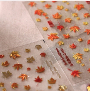 Close-up of 3D autumn maple leaf nail stickers with metallic gold relief and red art details