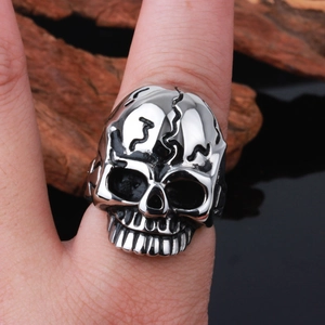 Close-up of a silver stainless steel skull ring on a finger with a vintage wood background