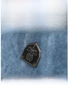 Close-up of vintage denim fabric texture and black metal logo plate on stylish backpack