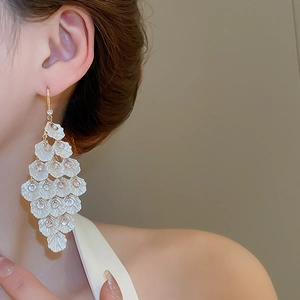 Close-up of cascading white shell-textured petals with sparkling zircons on elegant drop earrings