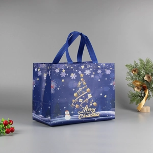 Detail of blue Christmas non-woven gift bag with golden reindeer and snowflake patterns