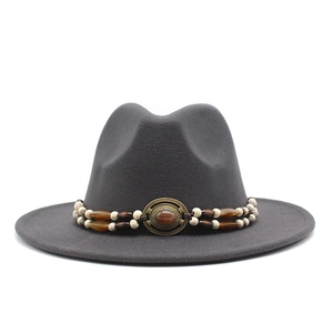 Detail of dark grey fedora hat with double-layered beaded band and vintage metal emblem