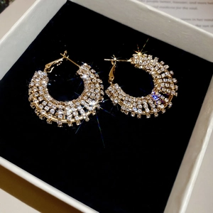 Macro detail of gold-plated hoop earrings featuring multiple rows of brilliant crystals