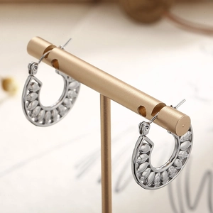 Silver hollow leaf round earrings in high-quality titanium steel on a gold T-stand