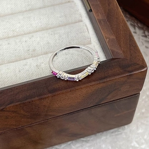 Macro shot of silver ring with colorful rectangular cubic zirconia on a wood jewelry box