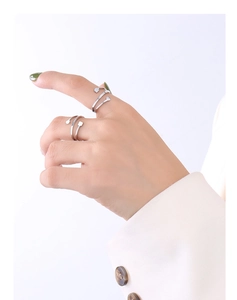 Close-up of geometric spiral open rings with round and square metal accents on a hand