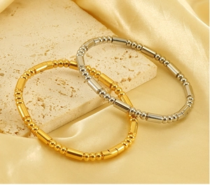 Detail view of 18K gold and silver bamboo bead bracelets on yellow silk fabric