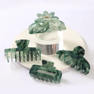 Set of four dark green marble pattern hair claws in various sizes on a white background