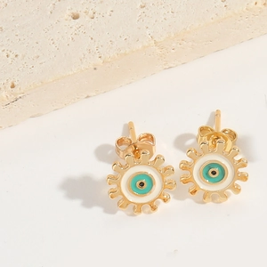 Close-up of golden evil eye gear stud earrings with turquoise and white enamel details