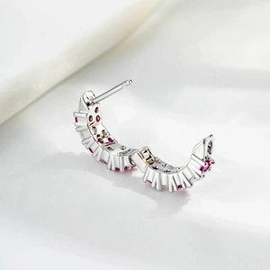 Silver C-shaped hoop earring with micro-set red zircon stones on a white background