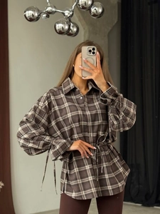Detail of vintage brown plaid shirt showing the drawstring waist and textured fabric