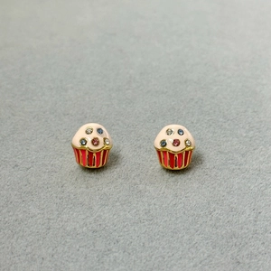 Detailed macro shot of cupcake earrings with colorful crystals on a gray velvet display