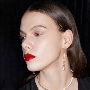 Close-up of elegant long tassel rhinestone earrings and layered necklaces on black velvet
