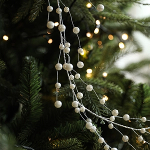 Elegant white pearl garland draped over green Christmas tree branches with warm lights