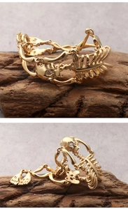 Detailed close-up of golden skeleton bone bracelet with zircon eyes on wood texture